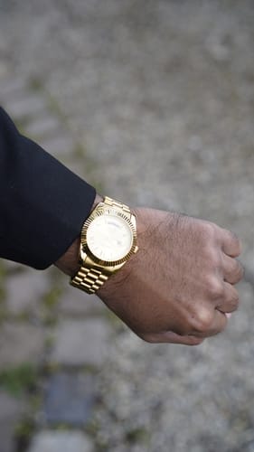 Customer showing their gold Lucky Fours® Santos watch on their wrist while wearing a black sleeve.