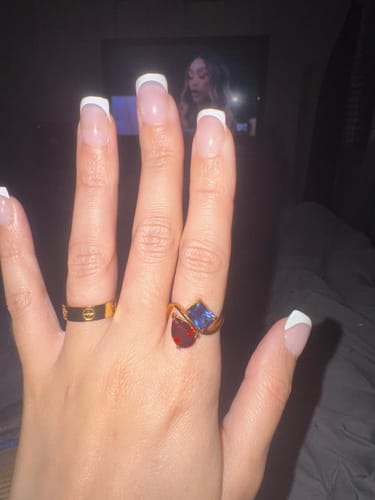 Customer wearing the gold Navae Birthstone Ring with a red pear-cut stone and a blue radiant-cut stone.