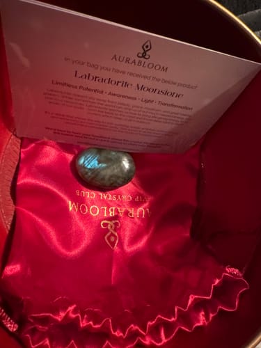 Reviewer's labradorite crystal and info card resting on a red satin pouch from the VIP Crystal Club.