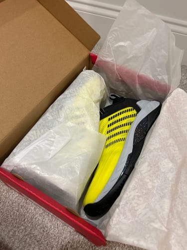 Customer's new HYPERCOURT SUPREME 2 shoe, bright yellow and black, shown partially wrapped inside the open box.