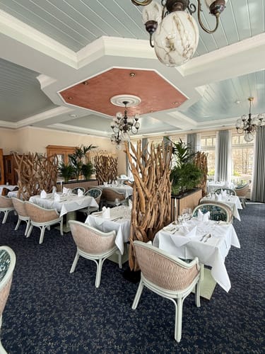 Kunde zeigt den Design Raumteiler BLUMA als stilvolle Trennwand zwischen Tischen in einem Restaurant.