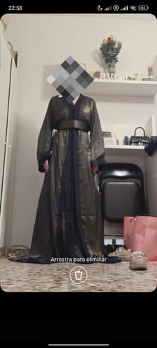 Reviewer showing a full-length view of the shiny gold Lebsa Joud, a long robe with dark trim and a wide belt.