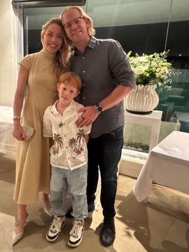 Customer and family smiling beside the beautiful White Purity Vase Arrangement on a pedestal.