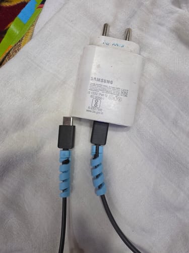 Customer's two light blue spiral Cable Protectors on black charging cables plugged into a white adapter.