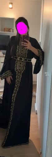 Customer in a full-length view of the elegant black Dana caftan with gold embroidery.