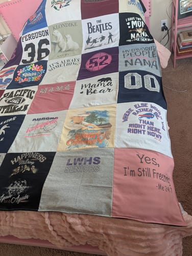 Customer's colorful Project Repat T-Shirt Quilt spread out fully on a bed, showing the patchwork of different shirts.