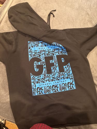 Customer's black MADE HOODIE laid flat, showing the large blue and black graphic with 'GFP APPAREL COMPANY' on the chest.