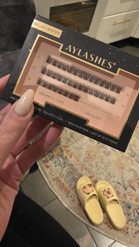 Eine Kundin hält die geöffnete Schachtel der AYLASHES 'LIKE A LADY' Wimpern.