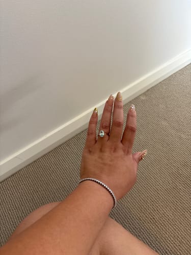 Customer's hand wearing the Aura Birthstone Ring with its large, light blue oval stone.