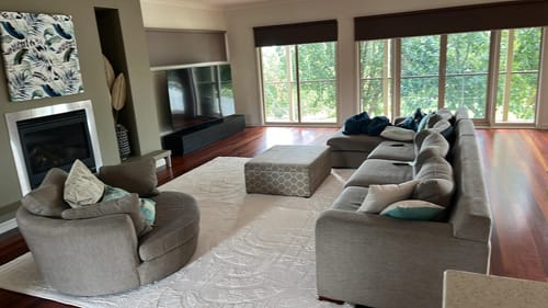 Customer's large, light-colored Mellow Mat in their modern living room with a grey sofa and armchair.
