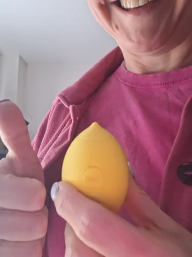 Reviewer smiling and giving a thumbs-up while holding the yellow Lem Clitoral Massager.