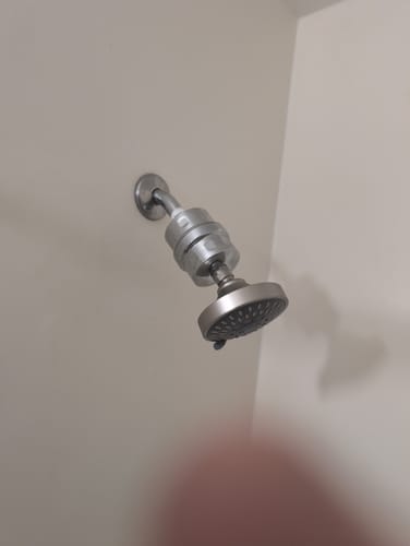 Partial view of a reviewer's installed silver shower filter containing the replacement cartridge.