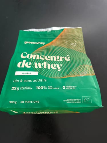 Un client montre le sachet vert de 900g de Concentré de whey bio, saveur vanille.