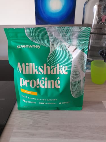 Photo d'un client du sachet vert de Milkshake protéiné à la mangue, posé sur un comptoir.