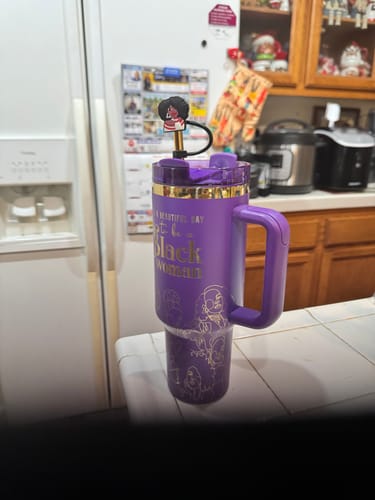 Customer's purple 'Purple Reign' tumbler with gold lettering and a decorative straw topper, on a kitchen counter.