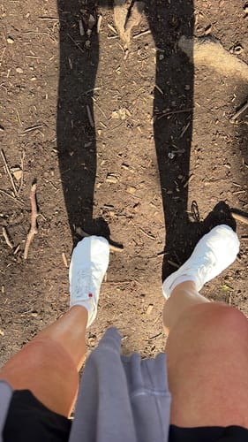 Reviewer's top-down view of their white Smart I barefoot shoes while standing on a dirt path.
