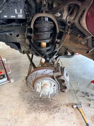 Close-up of the reviewer's front leveling lift kit during installation on the truck's suspension.