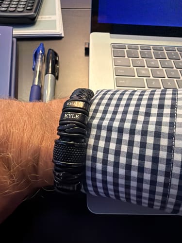 Customer wearing the personalized black bracelet on their wrist while at a desk.