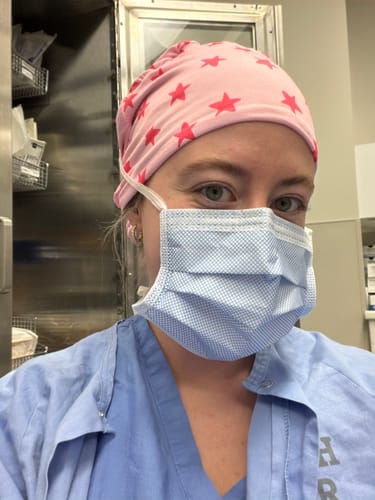 Reviewer wearing their pink DuoStyle Scrub Hat with a hot pink star pattern in a clinical setting.