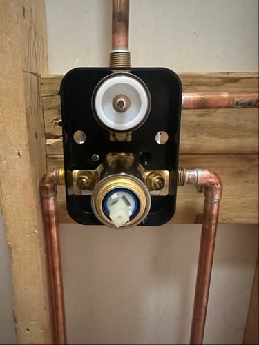 Close-up of a customer's black 2H Valve Diverter Replacement connected to copper pipes during installation.