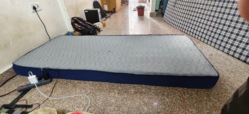 Customer's Flo Mattress Ortho with a grey patterned top and blue sides, placed on a room floor.