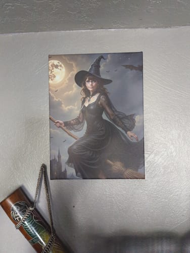 Customer's 'The Poised Witch' canvas portrait of a witch on a broom against a night sky, hanging on a wall.