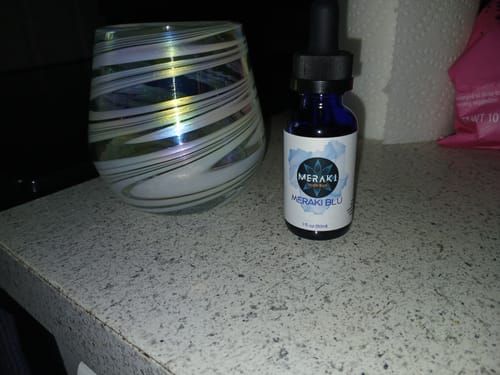 Customer's blue bottle of Meraki Blu Methylene Blue with a black dropper, shown on a speckled counter.