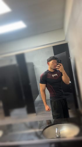 Customer wearing the fitted, black and maroon Warrior X Compression Tee in a locker room selfie.