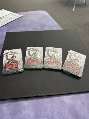 Customer displays four shrink-wrapped packs of 'Young Washington' tickets on a table.