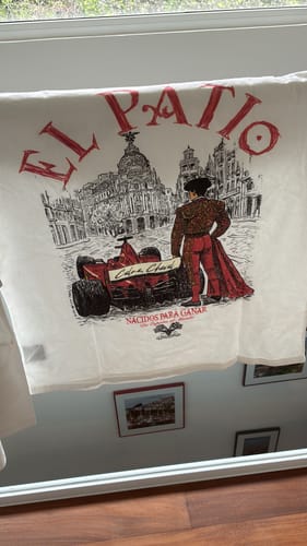Reviewer's white LA CAMISETA RACING long sleeve shirt laid out, showing the graphic of a torero and a red F1 car.