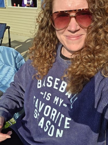 Reviewer outdoors in a blue corded 'Baseball Is My Favorite Season' sweatshirt.