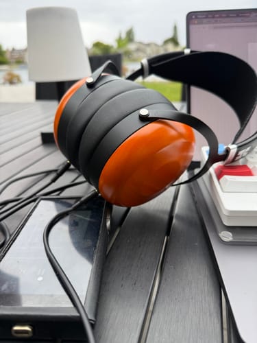Customer's Hifiman Sundara headphones with wooden ear cups resting on a slatted outdoor table.