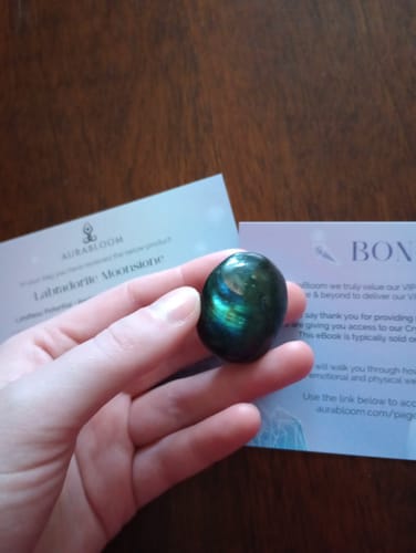 Reviewer holding a small, polished Labradorite moonstone in the palm of their hand.