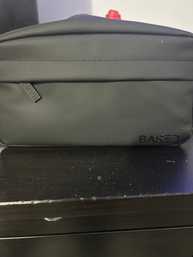 Customer's black toiletry bag resting on a dark wooden surface.