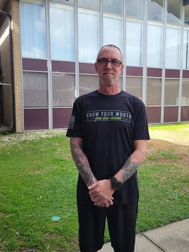 Reviewer standing outdoors wearing a black graphic t-shirt with 'KNOW YOUR WORTH' printed on the front.