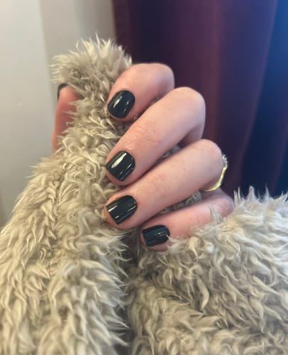 Reviewer's hand showing a glossy black manicure created with the Holy Gels Starter Kit.