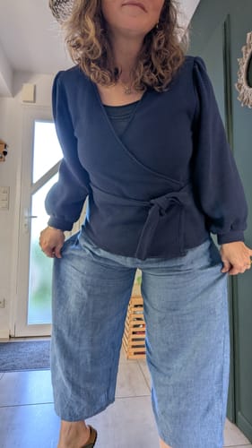 Cliente montrant la coupe ample de son pantalon Briac en lin bleu.