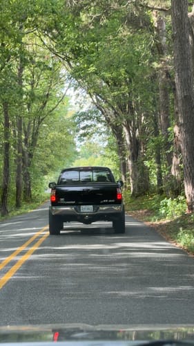 Reviewer's black truck with 2-inch wheel spacers driving down a tree-lined road, showing a wider stance.