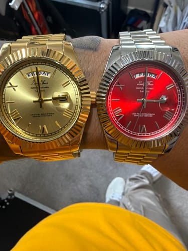 Reviewer wearing two Lucky Fours® Santos watches on one wrist: one is gold and the other is silver with a red face.