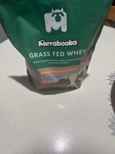 Customer's green bag of Mirrabooka Grass Fed Whey protein in Natural Mocha Latte flavour, sitting on a countertop.