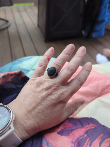 Customer's hand resting outdoors, wearing the black Oversize Oval Silicone Ring.