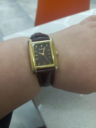 Reviewer wearing the Olivia Gold Burgundy Leather watch on their wrist, showing its rectangular gold case.