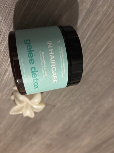 Client montrant le pot de Gelée Détox posé sur une surface en bois.