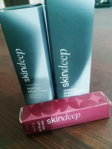 Customer's box for DREAM GLAZE - Peptide Milk Toner, alongside other Skindeep products on a wooden table.