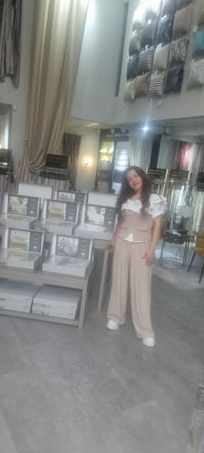 O clientă poartă setul complet Gamille, format din pantaloni și top bej, într-un magazin.