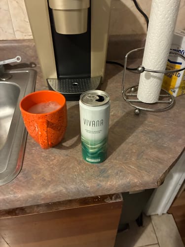 Customer's opened can of VIVANA INFUSED 12OZ on a kitchen counter next to an orange mug.