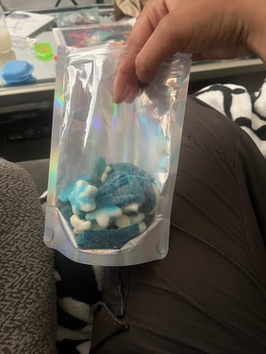 Customer holding a holographic pouch containing the blue and white Blue Raspberry Mix candy.