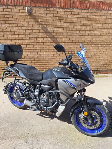 Customer's black Wind Rider Seat Cover fitted over the seat of a motorcycle parked outdoors.