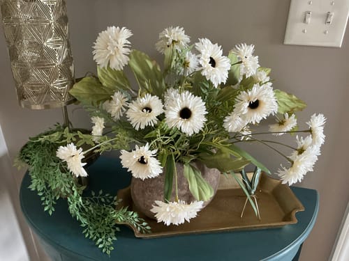 Customer's full arrangement of White Daisy Stems in a vase, displayed on a side table.