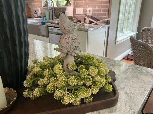 Reviewer's Willow Buds Candle Ring styled around a bird figurine on a dark wooden tray.